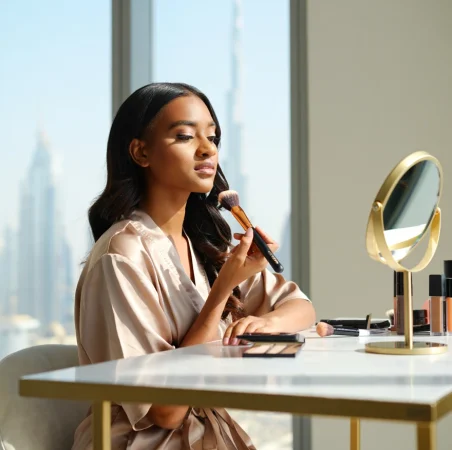 Woman applying makeup at a vanity with Dubai skyline in the background